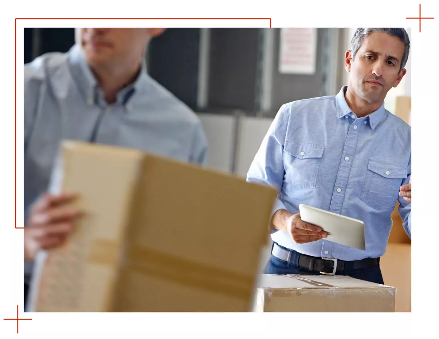 Two men are sitting at a table with boxes.